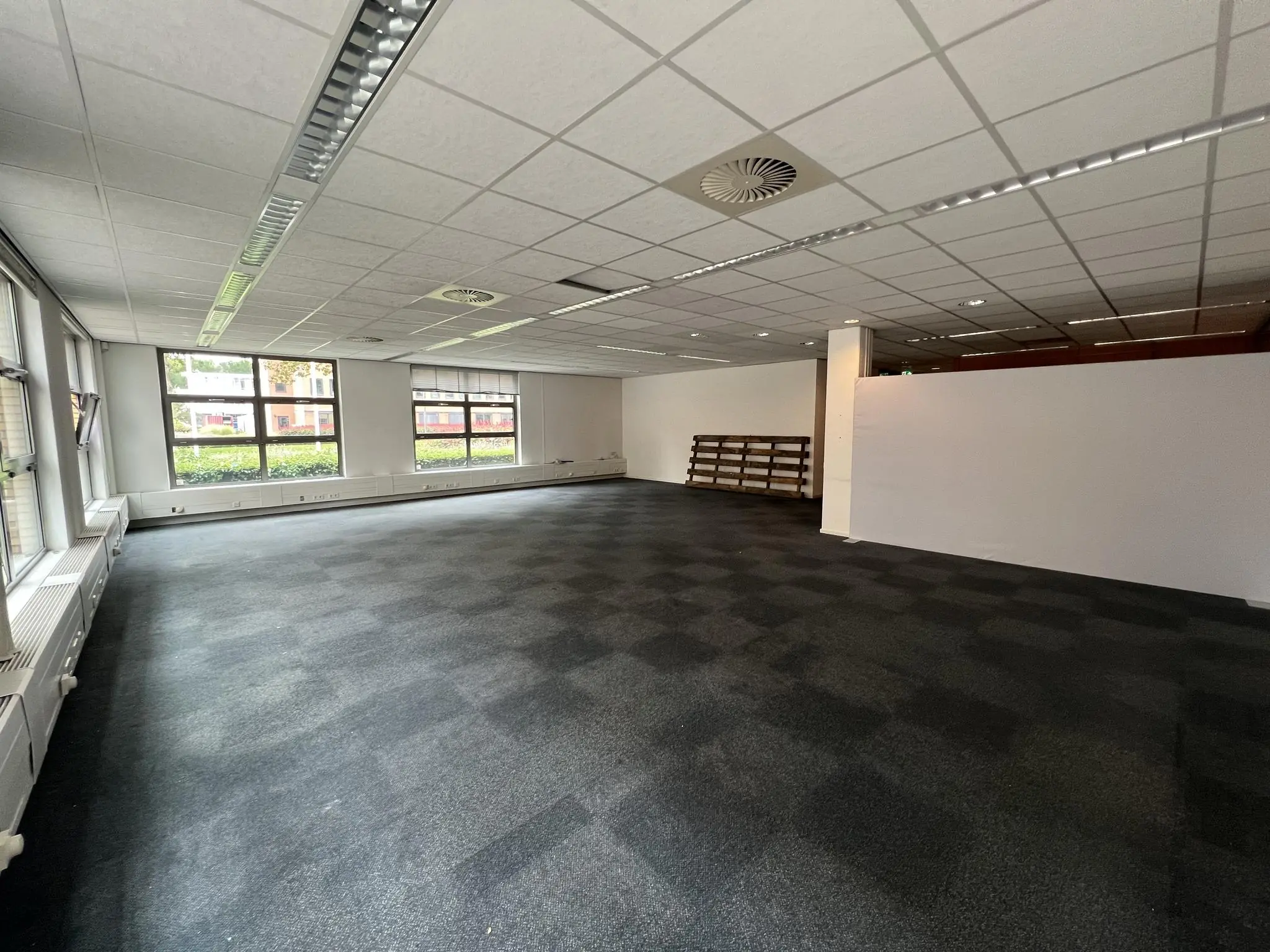 Leeg kantoorpand aan de Rivium 2e Straat met grote ramen en systeemplafond.